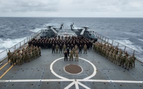 Members from all services pose for a contingent photo in front of two NH90 Helipcopters on the flight deck of HMNZS Canterbury en route to the soloman islands for OP Moa 2024.