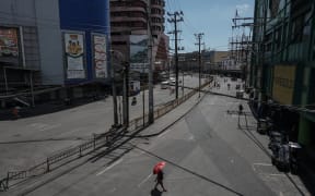 A woman with umbrella walks along a deserted street at Divisoria public market in Manila, Philippines on April 01, 2020.