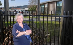 Concerned library patron Barbara Barwick stands in front of a new fence which has blocked her shortcut to the library. The $6700 fence has drawn the ire of some in the community.