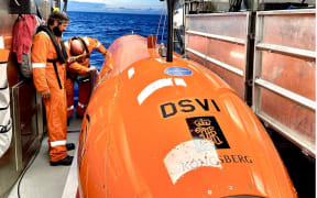 A man in an orange suit prepares to launch a Deep Sea Vision submersible.