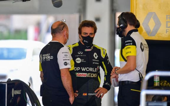 Renault's Spanish driver Fernando Alonso (C) speaking with engineers ahead of taking part in a testing run on the Bahrain International Grand Prix track in November 2020.