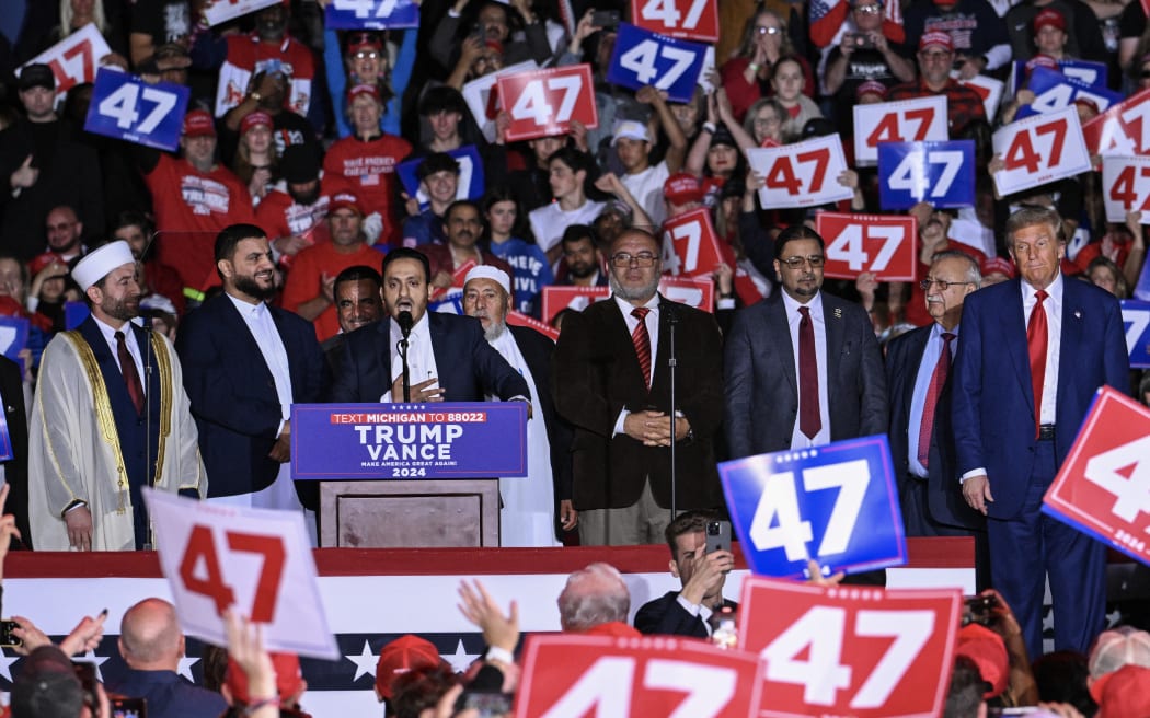 Former US President and Republican presidential candidate Donald Trump stands with local leaders of the Muslim community as they endorse him during a campaign rally at the Suburban Collection Showplace in Novi, Michigan, 26 October, 2024.