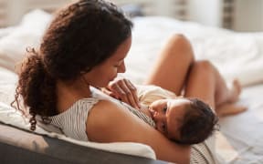 A darkhaired mother breastfeeds her darkhaired baby