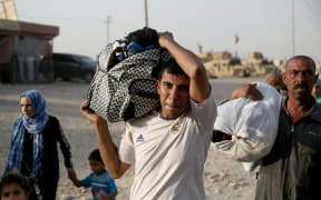 Iraqis fleeing from IS controlled areas of Mosul arrive at Al Qayyarah, a town secured by the Iraqi Army.