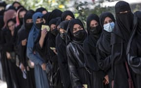 Afghan female students stand in a queue after arriving for entrance exams at Kabul University on 13 October, 2022.