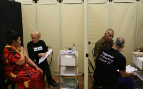 Malia Su-emalo Lui (left cubicle) and Seumanu Va'a Robertson (right) receive information about Covid-19 vaccination before receiving the jab at a public vaccination event arranged by the Catholic Church in Wellington, 9 June 2021.