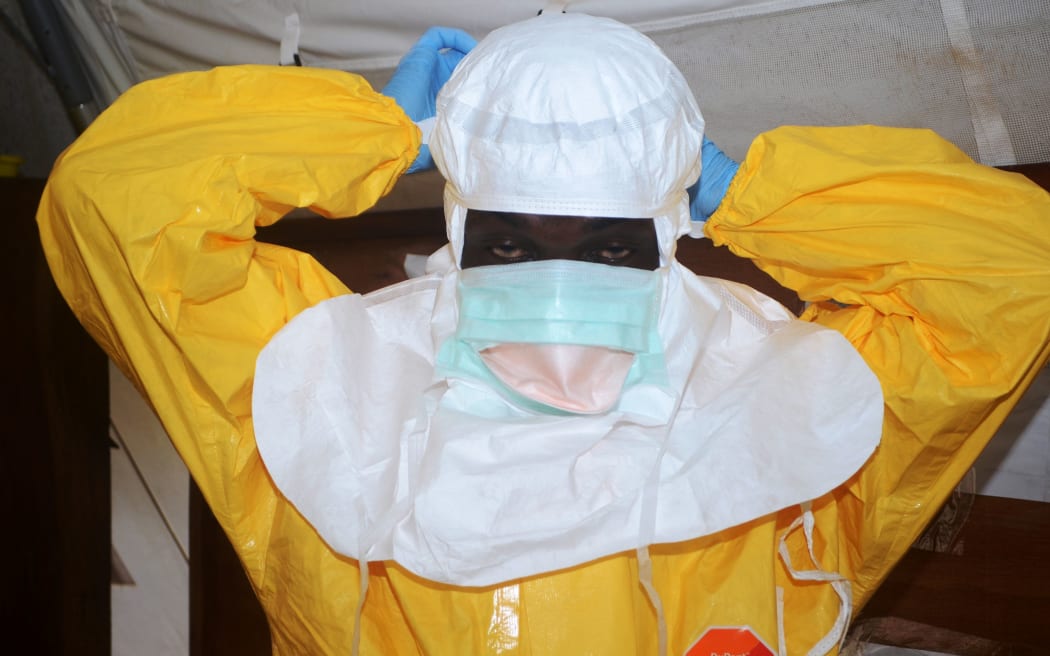 A member of Doctors Without Borders puts on protective gear in an isolation ward.