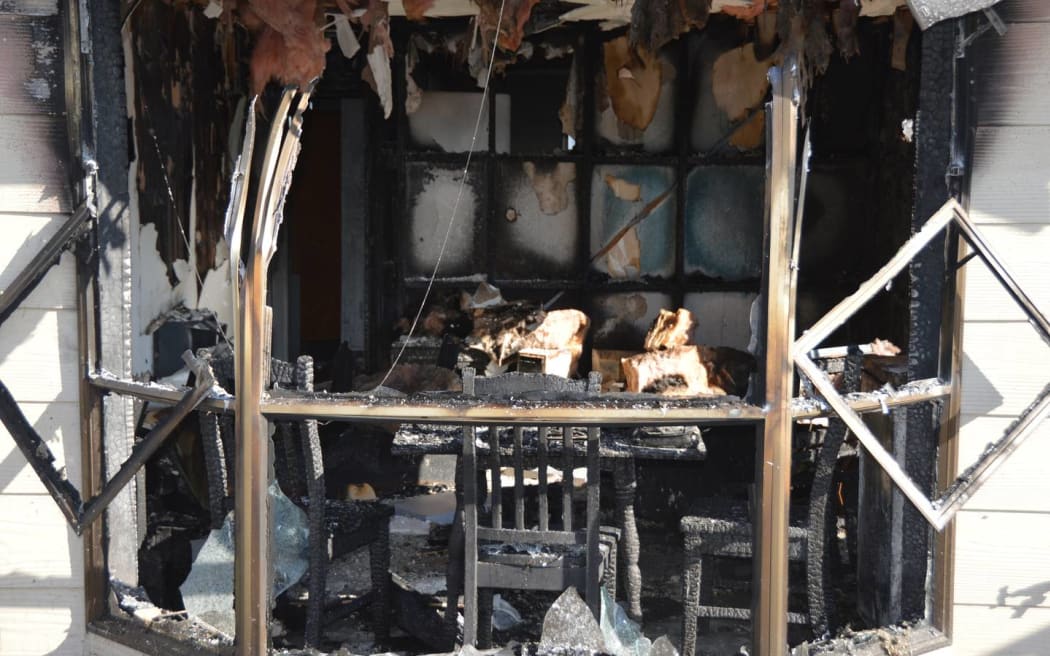 Fire damage to the house is visible from the street.
