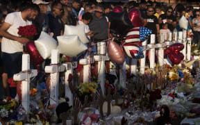 People pray and pay their respects at the makeshift memorial for victims of the shooting that left a total of 22 people dead in El Paso.