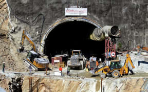 Rescue workers stand at an entrance of the under construction road tunnel, days after it collapsed in the Uttarkashi district of India's Uttarakhand state on November 18, 2023.