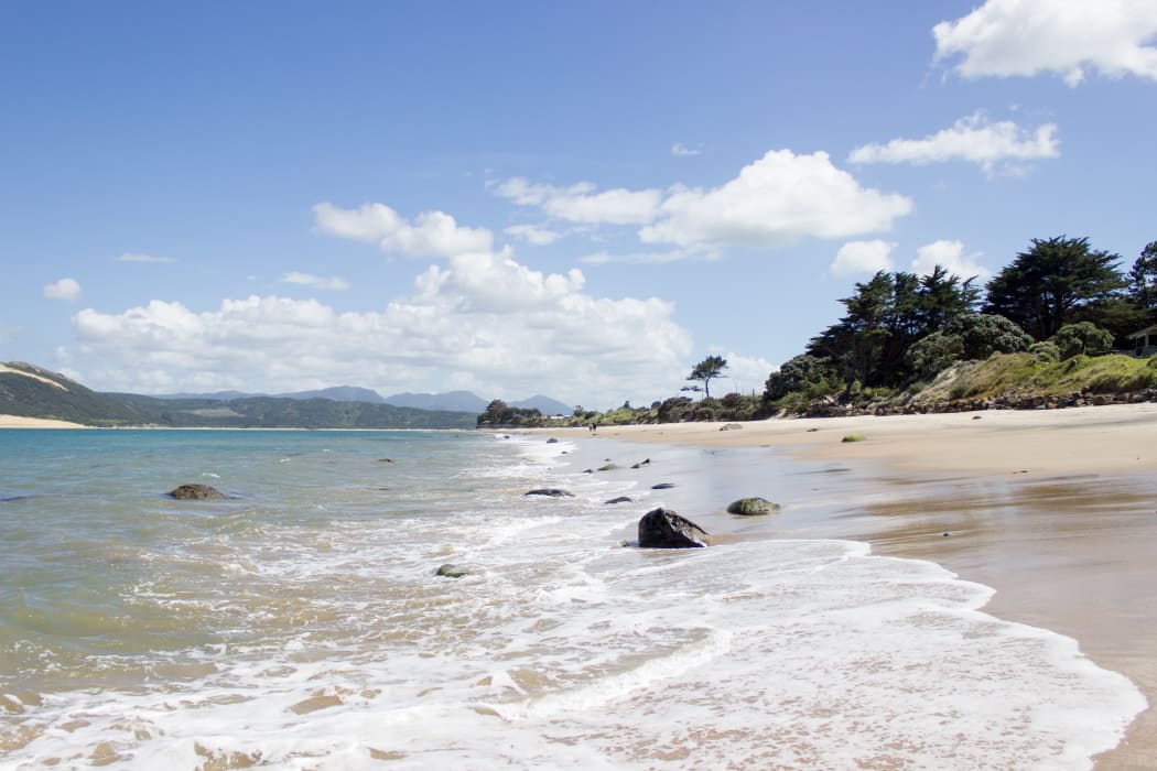 The tide comes in at the beach in Omapere, New Zealand.