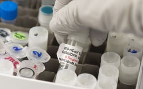 (FILES) In this file photo Dr. Nita Patel, Director of Antibody discovery and Vaccine development, lifts a vial with a potential coronavirus, COVID-19, vaccine at Novavax labs in Rockville, Maryland on March 20, 2020, one of the labs developing a vaccine for the coronavirus, COVID-19.