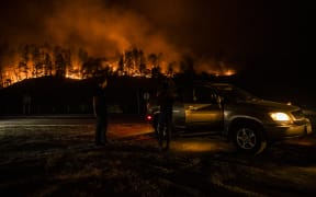 People stop on the side of the road to watch as the Glass Fire slowly blazes down the hill side outside of Calistoga in Napa Valley, California on 28 September 2020.