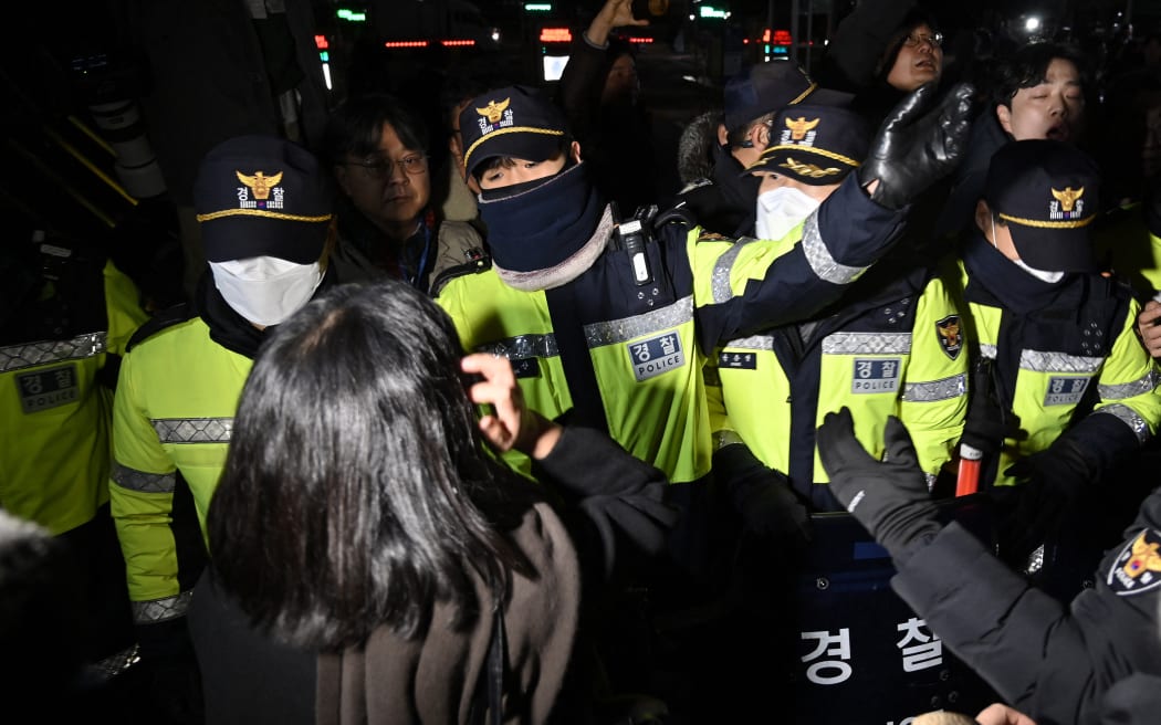 Police attempt to hold back people trying to enter the National Assembly in front of the main gate of the National Assembly in Seoul, South Korea on December 3, 2024, after President Yoon Suk Yeol declared emergency martial law. - South Korea's President Yoon Suk Yeol on December 3 declared emergency martial law, saying the step was necessary to protect the country from "communist forces" amid parliamentary wrangling over a budget bill. (Photo by JUNG YEON-JE / AFP)