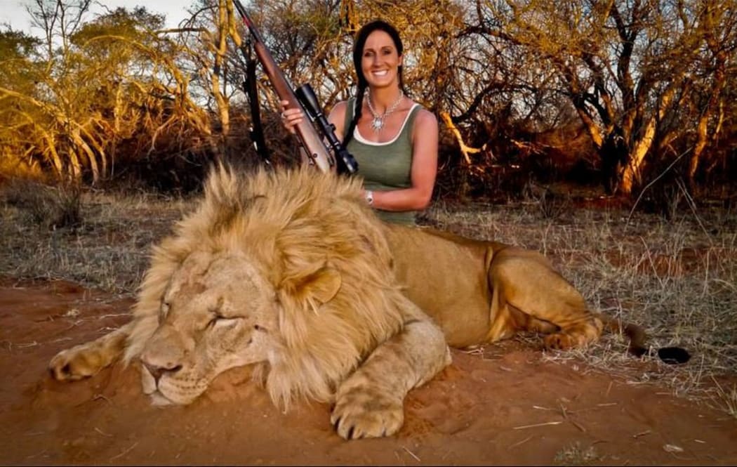 Melissa Bachman holding a gun over the carcass of a lion