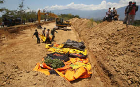 Officers bring the bodies of victims of the earthquake and tsunami to bury them in Palaroa village, in the city of Palu, Central Sulawesi, Indonesia.