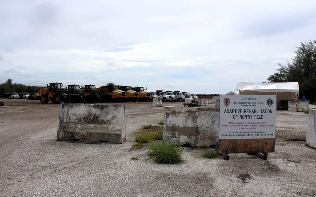 A parking lot with a "no parking" sign, featuring several bulldozers at the entrance of a U.S. Air Force rehabilitation site in near Tinian’s North Field.