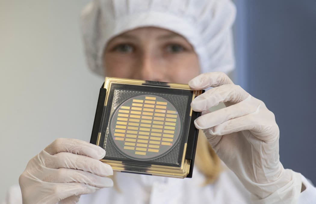 Engineer Hannah Wagenknecht shows a wafer with photonic chips for quantum computing at the technology company Q.ant in Stuttgart, southern Germany, on September 14, 2021. - The company works on chips with customized waveguides for optical data processing, that are "considered the central building block for bringing quantum technologies out of the labs and into everyday products", according to the Q.ant. (Photo by THOMAS KIENZLE / AFP)