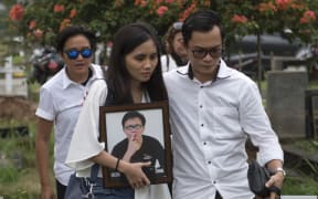 The sister of Hizkia Jorry Saroinsong, a passenger on the Lion Air flight, carries her brother's portrait during his funeral in Jakarta.