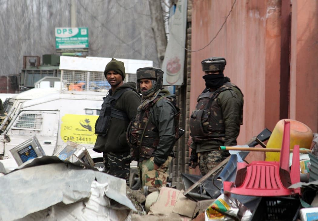 Indian paramilitary soldiers stand guard near the encounter site where nine people were killed in fierce gun-battle between militants.