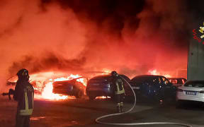 This handout image taken and released on March 31, 2025, by the Vigili del Fuoco, the Italian Corps of Firefighters, shows firefighters working to put out a fire at a Tesla dealership, in which 17 cars were destroyed or seriously damaged, in Torrenova, on the outskirts of Rome. (Photo by Handout / Vigili del Fuoco / AFP) / RESTRICTED TO EDITORIAL USE - MANDATORY CREDIT "AFP PHOTO / VIGILI DEL FUOCO" - NO MARKETING NO ADVERTISING CAMPAIGNS - DISTRIBUTED AS A SERVICE TO CLIENTS