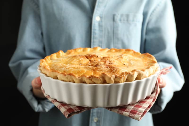 Woman with homemade pie on black background, closeup