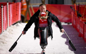 Corey Peters of New Zealand holding Shuey Rhon Rhon, mascot of the Beijing 2022 Winter Paralympic Games in his mouth, celebrates after winning the men's downhill sitting event at the Yanqing National Alpine Skiing Centre on March 5, 2022.