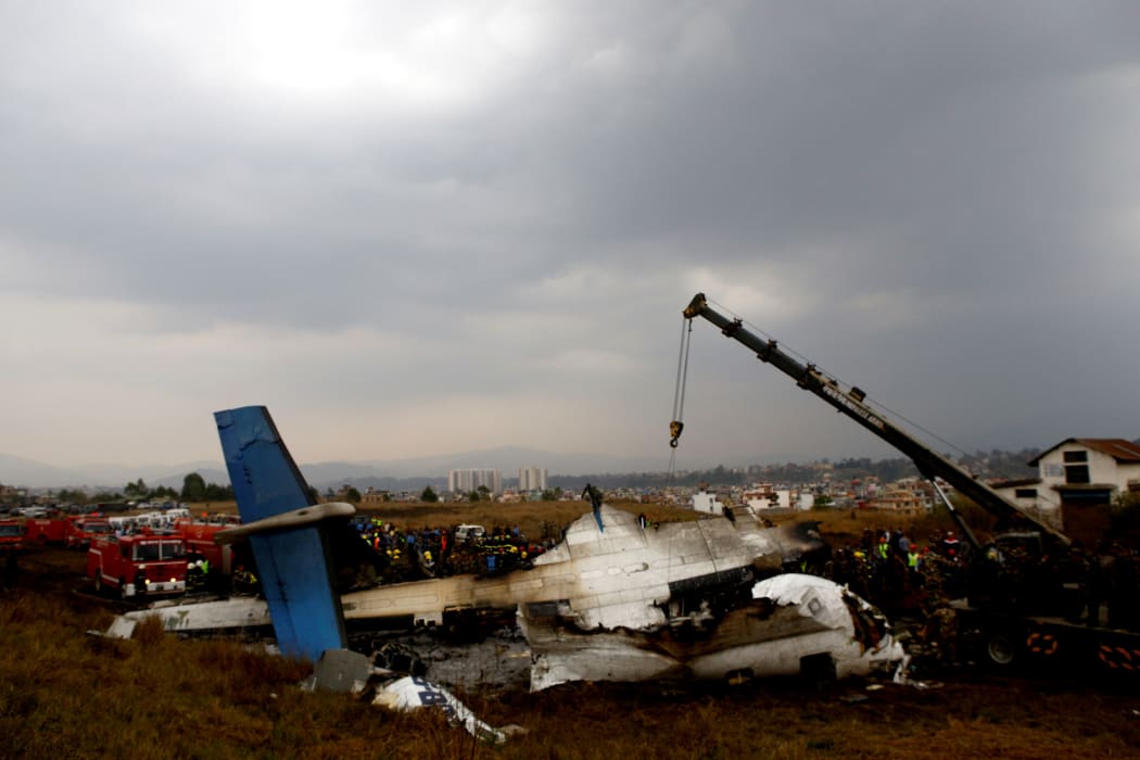 Nepali rescue workers gather around the debris of an airplane that crashed near the international airport in Kathmandu on March 12, 2018.
