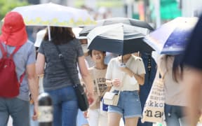 People walk in strong sunshine in Kyoto on July 4, 2023.