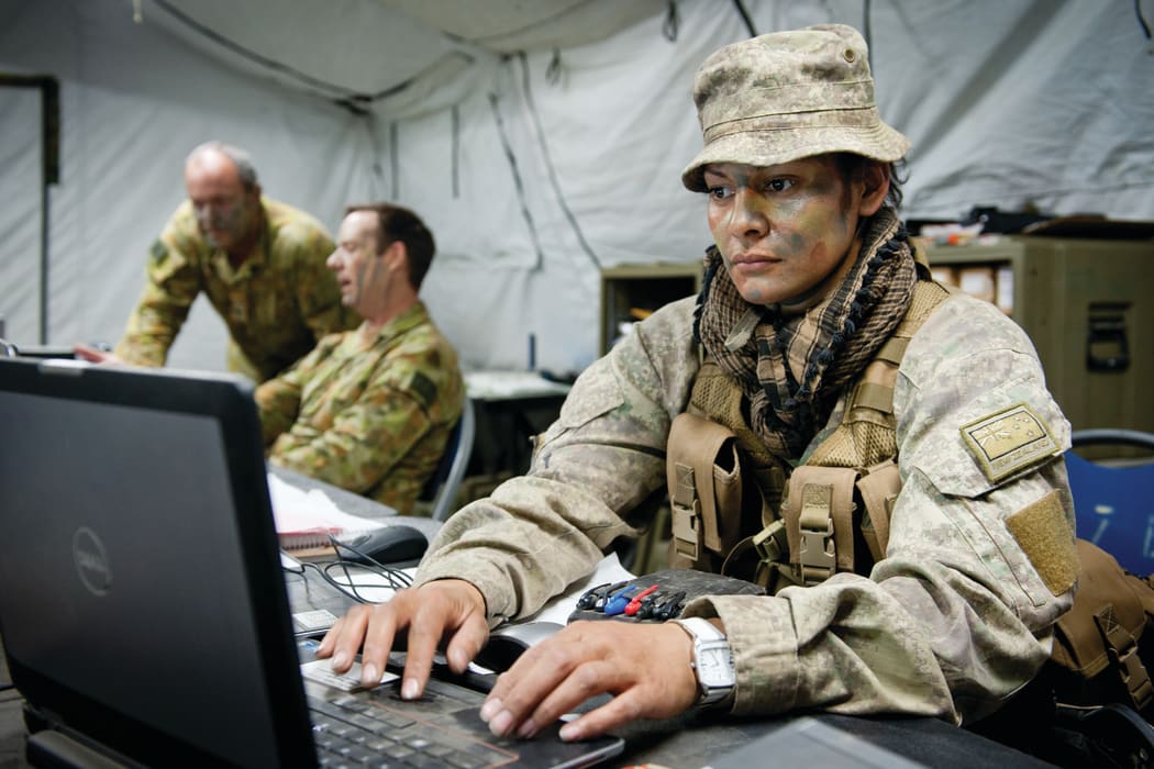 Member of the New Zealand Defence Force on a laptop in uniform