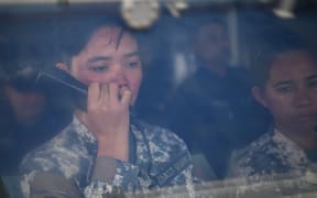 This photo taken on August 22, 2023 shows a female member of the Philippine coast guard issuing a radio challenge to a Chinese coast guard ship during the re-supply mission by a civilian boat chartered by the Philippine navy to deliver supplies to Philippine navy ship BRP Sierra Madre in the disputed South China Sea. A team of AFP journalists on board the BRP Cabra, one of the two Philippine Coast Guard escort boats, watched as one of the Chinese ships came within several meters of the vessel. AFP was one of three media outlets given the rare opportunity to join the Philippine resupply mission to Second Thomas Shoal, less than three weeks after Chinese coast guard ships water cannoned a similar replenishment operation. (Photo by Ted ALJIBE / AFP)