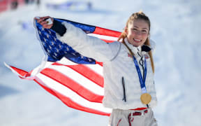USA's gold medalist Mikaela Shiffrin celebrates with her national flag during the podium ceremony of the women's slalom event at the 2026 Winter Olympics.