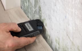 Person Hand Measuring The Wetness Off A Moldy Wall