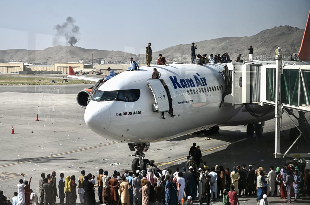 People climb on top of a plane at Kabul's airport on 16 August 2021, as thousands tried to flee the Taliban.