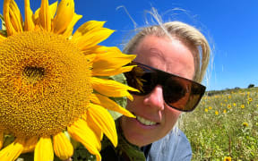 Rachel Short poses with one of her sunflowers.
