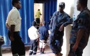 Staff look on as the room of a refugee diagnosed with typhoid fever is cleaned at Hillside house.