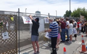 Families of those who died tie their placards to the fence surrounding the CTV site.