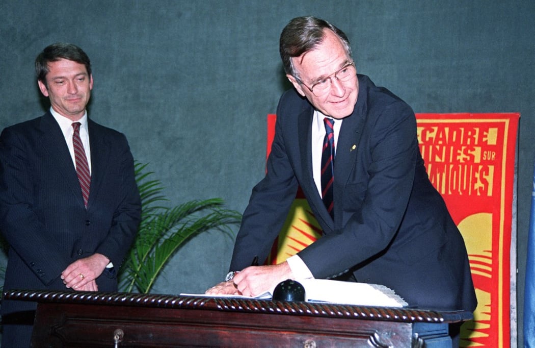 US President George Bush signs the United Nations Climate Change convention, 12 June 1992 in Rio de Janeiro, during the UN-sponsored Earth Summit. (Photo by J. DAVID AKE / AFP)