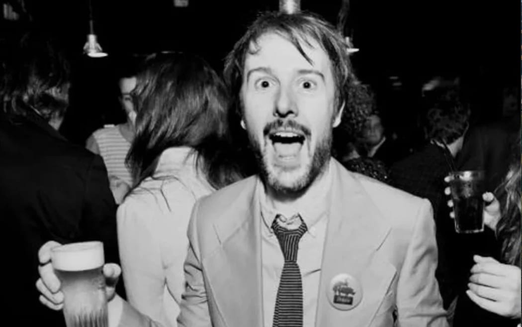 Stefaan Van Leuven is a happy-looking man in a suit holding a beer.