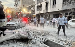 People gather outside a building that was hit by an Israeli strike in Tehran on 13 June, 2025.
