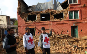 Members of the Nepal Red Cross look at a damaged building in Kathmandu.