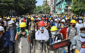 Protesters wearing protective gear gather on a road during a demonstration against the military coup in Yangon on 3 March