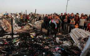 Palestinians look at the destruction after an Israeli strike where displaced people were staying in Rafah, Gaza Strip, Monday, May 27, 2024. Palestinian health workers said Israeli airstrikes killed at least 35 people in the area. Israel's army confirmed Sunday's strike and said it hit a Hamas installation and killed two senior Hamas militants. (AP Photo/Jehad Alshrafi)