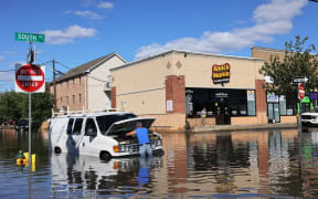 Abilio Viegas attempts to fix his flooded van on South Street on 2 September, 2021 in Newark, New Jersey.