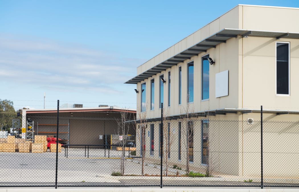 Modern office building with industrial warehouse and workshop  on the rear plan.