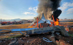fire and smoke rise from the tail section of a Jeju Air Boeing 737-800 series aircraft after the plane crashed and burst into flames at Muan International Airport in South Jeolla Province, some 288 kilometres southwest of Seoul on December 29, 2024. - A Jeju Air plane carrying 181 people from Bangkok to South Korea crashed on arrival on December 29, authorities told AFP, with 29 confirmed dead and dramatic video showing the aircraft bursting into flames. (Photo by YONHAP / AFP) / - South Korea OUT / NO USE AFTER JANUARY 8, 2025 02:48:46 GMT -  - SOUTH KOREA OUT / NO ARCHIVES -  RESTRICTED TO SUBSCRIPTION USE