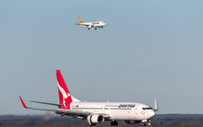 Sydney, Australia - May 5, 2014: Qantas Boeing 737-800 aircraft at Sydney Airport with a Tiger Airways Airbus A320 on approach in the background.