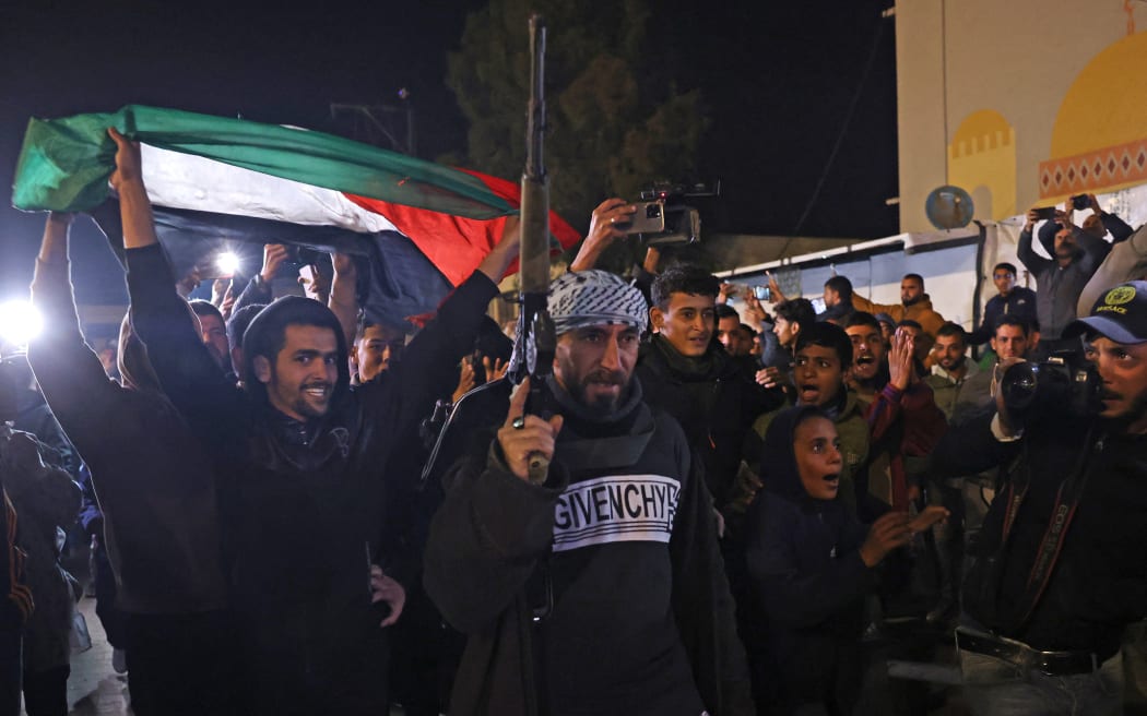 People celebrate along a street in Khan Yunis in the southern Gaza Strip on January 15, 2025, amid the ongoing war in the Palestinian territory between Israel and Hamas. Thousands of Gazans celebrated on January 15 as news spread that a ceasefire and hostage release deal had been reached between Israel and Hamas, aimed at ending more than 15 months of war in the Palestinian territory. (Photo by BASHAR TALEB / AFP)
