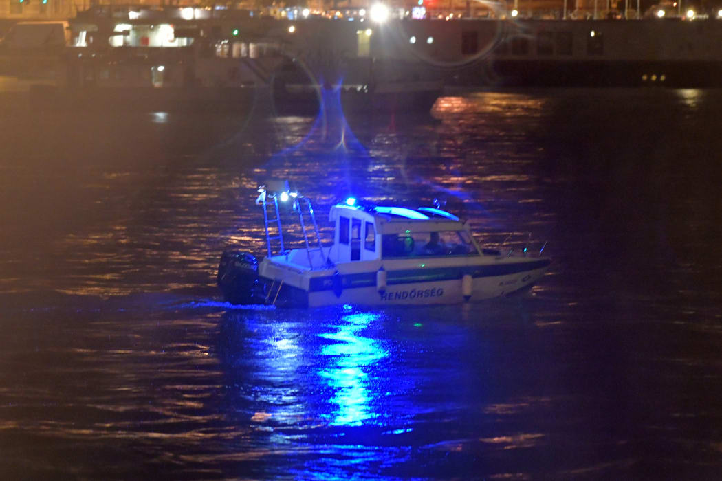 Crew-members of a police boat search for survivors after a riverboat capsized on the Danube River in Budapest.