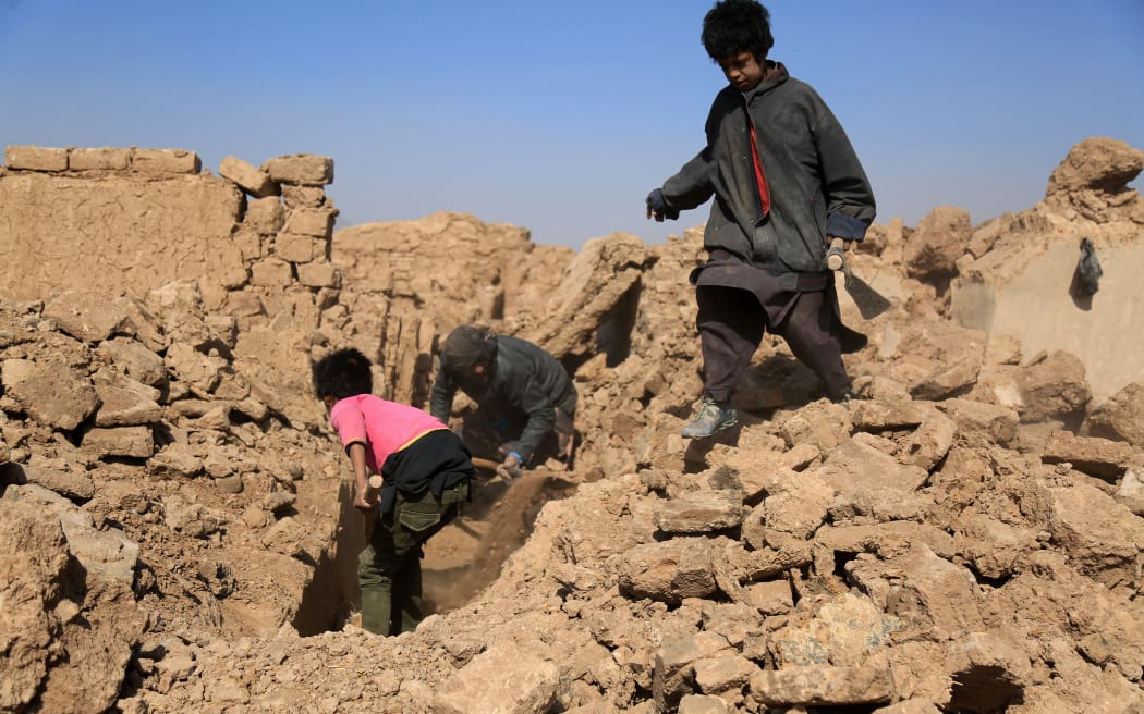 Afghan residents clear the debris of houses that were damaged in a series of earthquakes, in Injil district of Herat province on October 15, 2023. A magnitude 6.3 earthquake killed two people in western Afghanistan on October 15, with damaged prisons emptied and residents fleeing a region where tremors have claimed at least 1,000 lives this past week. (Photo by Mohsen KARIMI / AFP)